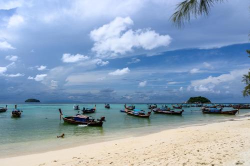 a group of boats in the water on a beach at Wapi Resort in Ko Lipe