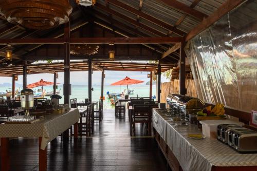 un restaurant avec des tables et des chaises et l'océan dans l'établissement Wapi Resort, à Koh Lipe