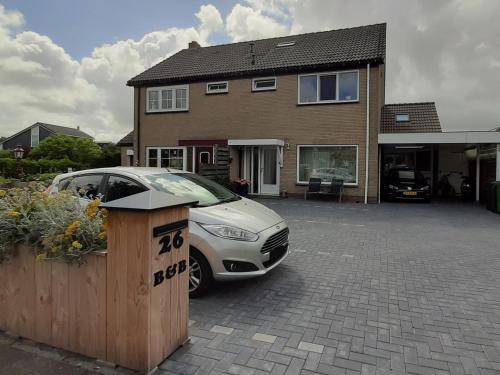 un coche aparcado frente a una casa en B&B Marijke, en De Koog