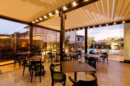 un restaurante con mesas, sillas y luces en Art Hotel Ventaglio, en Bardolino