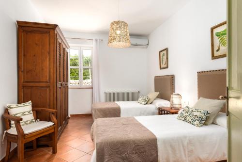 a hotel room with two beds and a chair at Llucasaldentet in Alaior