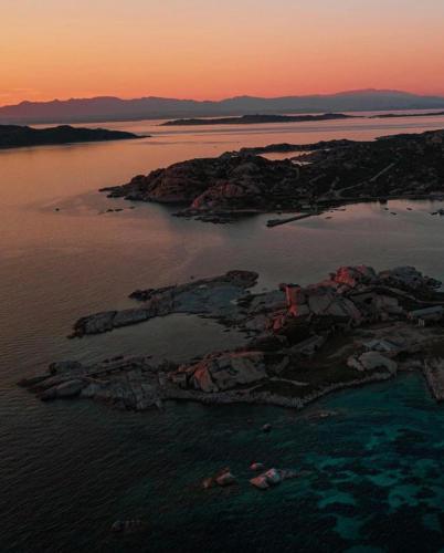 an island in a body of water at sunset at Residenze L'Isola Surf House in Porto Pollo