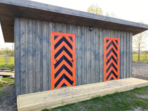 a wooden shed with orange and black stripes on it at Jaagu-Mihkli Muhu Island in Ridasi