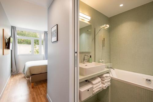 ein Bad mit einer Badewanne, einem Waschbecken und einem Bett in der Unterkunft NEW - Appt style le Corbusier avec Balcon - 8 pers in Paris