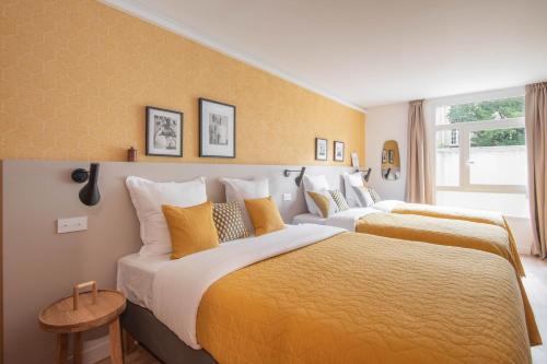 2 Betten in einem Hotelzimmer mit gelben Wänden in der Unterkunft NEW - Appt style le Corbusier avec Balcon - 8 pers in Paris