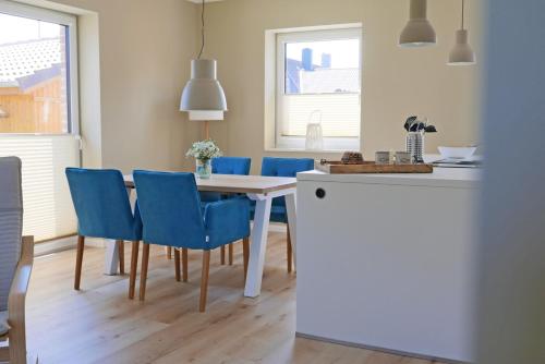 a kitchen and dining room with a table and blue chairs at Borbyer Perle in Eckernförde