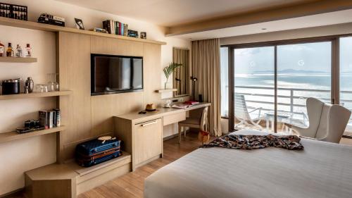 パタヤ・ノースにあるPullman Pattaya Hotel Gのベッド、デスク、テレビが備わるホテルルームです。