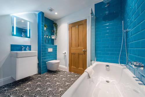 a blue bathroom with a tub and a toilet at City Centre, Newly Refurbished Stylish Apartment in Edinburgh