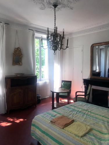 une chambre avec un lit, une table et un lustre dans l'établissement Villa BeauSoleil, à Digne-Les-Bains