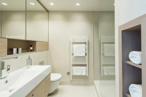 bagno con lavandino, servizi igienici e specchio di Brera Serviced Apartments Frankfurt Oper a Francoforte sul Meno