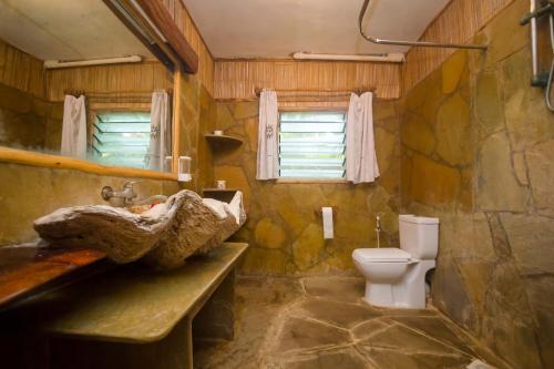 a bathroom with a stone sink and a toilet at Ziwa Beach Resort in Bamburi
