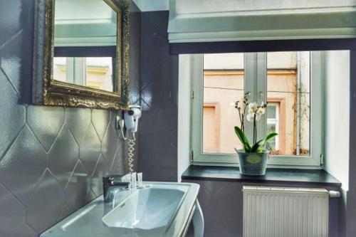 een badkamer met een wastafel, een spiegel en een raam bij Shalom Kazimierz in Krakau