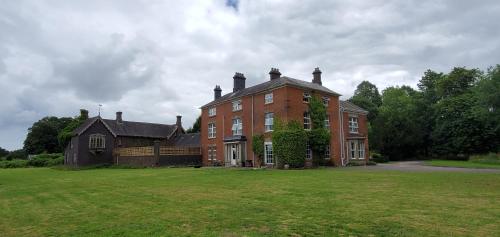 une grande maison en briques rouges avec une grande pelouse dans l'établissement Coundon Lodge Coventry, à Coventry