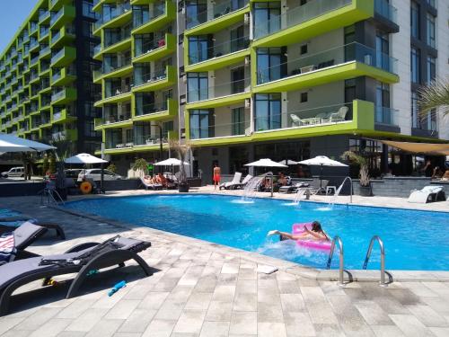 Studio Alezzi Beach Resort في مامايا نورد نافورداي: امرأة تسبح في مسبح في مبنى