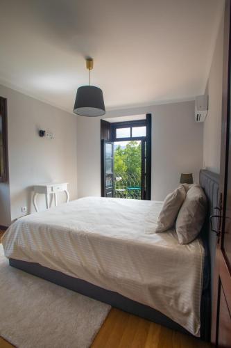 a bedroom with a large white bed with a window at Casa do Convento in Arcos de Valdevez