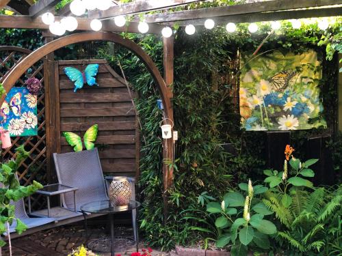 a garden with an arbor and a chair and butterflies at B&B overnachting de Margriet in Hardenberg