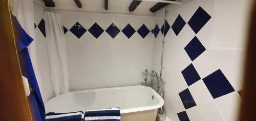 uma casa de banho com uma banheira branca e uma parede azul e branca em Quirky Cottage - Dogs Welcome - Free 24 hr Cancellation's em Corsham