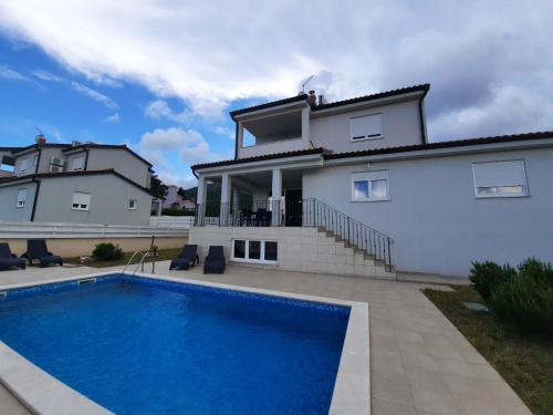 a villa with a swimming pool in front of a house at VILLA AURA YourCroatiaHoliday in Drenje