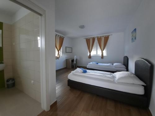 two beds in a room with wooden floors and windows at VILLA AURA YourCroatiaHoliday in Drenje