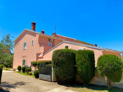 a pink house with bushes in front of it at Apartments Prodan in Fažana