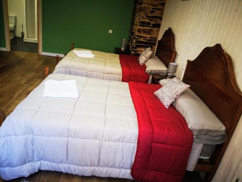 a bedroom with two beds with red and white blankets at Pensión Santa Rosa in Samos