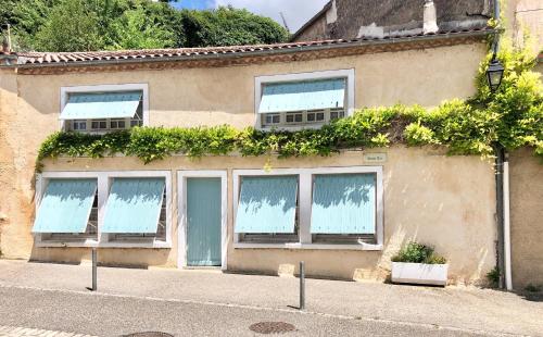 un bâtiment avec des fenêtres et des plantes sur son côté dans l'établissement Holiday Home Petite Maison Bleue, à Puy-lʼÉvêque