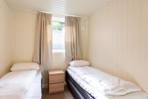 two beds in a small room with a window at Mo Gjestegård in Mo i Rana