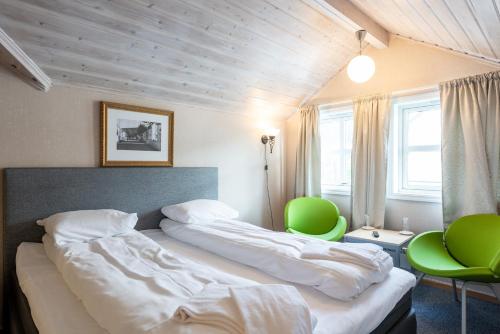 a bedroom with a bed and two green chairs at Mo Gjestegård in Mo i Rana
