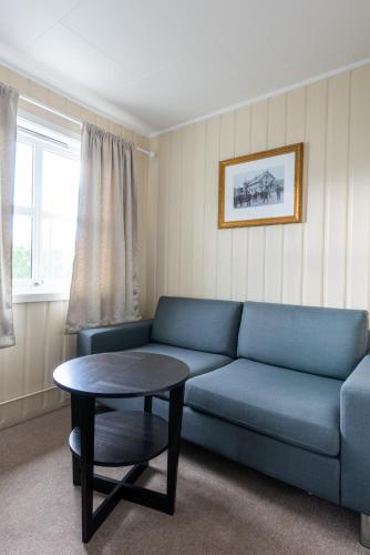 a living room with a blue couch and a table at Mo Gjestegård in Mo i Rana