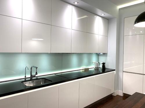 a kitchen with white cabinets and a sink at MONDRIAN Luxury Suites & Apartments Krakow Old Town in Krakow