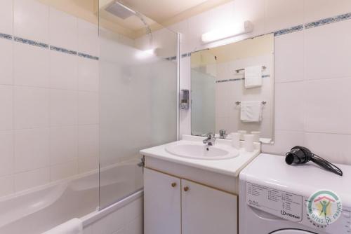 La salle de bains blanche est pourvue d'un lavabo et d'une baignoire. dans l'établissement Et si on restait en Normandie ?, à Caen