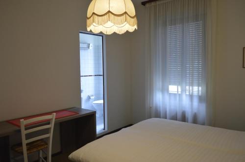 a bedroom with a bed and a desk and a window at Albergo Svizzero in Biasca