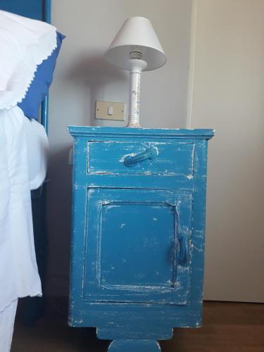a blue nightstand with a lamp on it next to a bed at B&B La Riundela in Asti