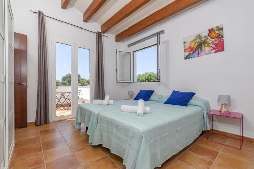 a bedroom with a large bed with blue pillows at Villa Astur in Binibeca