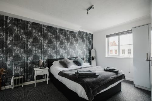 a bedroom with a bed with a black and white wallpaper at Hullidays - 'Old School Penthouse' Trinity Square in Hull