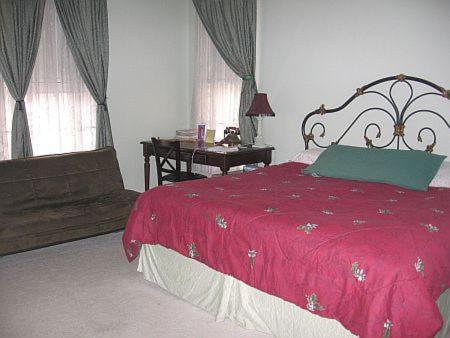 a bedroom with a red bed and a desk and windows at Olde Judge Mansion B&B in Troy