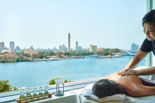 a woman and a man sitting on a balcony looking at the water at Four Seasons Hotel Cairo at Nile Plaza in Cairo