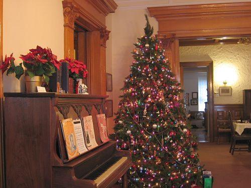 a christmas tree in a room with a piano at Olde Judge Mansion B&B in Troy