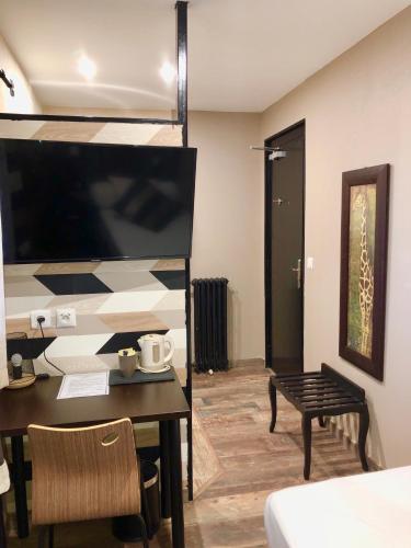 a living room with a table and a tv at Hôtel de Charme Le Provence in Salon-de-Provence