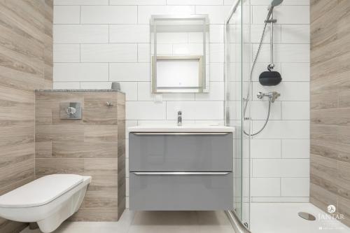 a bathroom with a toilet and a sink and a shower at Jantar Apartamenty - Perłowa Przystań in Kołobrzeg