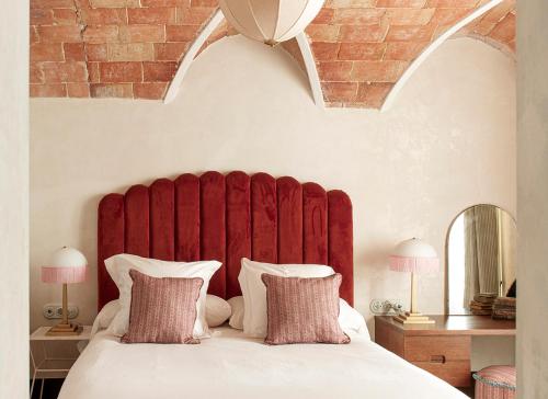 a bed with a red padded headboard in a bedroom at La Bionda Hotel - Adults Only in Begur