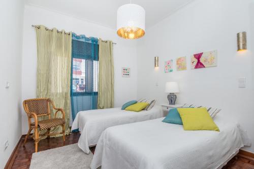 a bedroom with two beds and a chair and a window at Casa Jacarandá in Silves