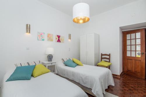 Dos camas en una habitación con paredes blancas. en Casa Jacarandá, en Silves