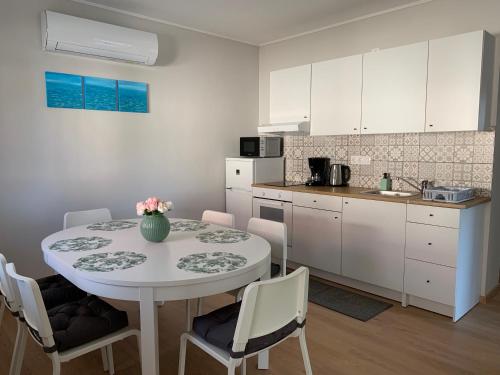 a kitchen with a table and chairs and a kitchen with white cabinets at Otthon a Balatonon Vendégház in Keszthely