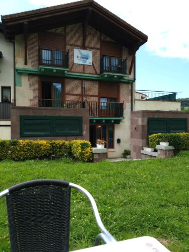 a chair in the grass in front of a building at Pension Paloma - Oiartzun in Oiartzun