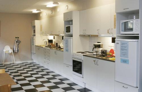 a kitchen with white cabinets and a checkered floor at Hotell Svanen in Kalmar