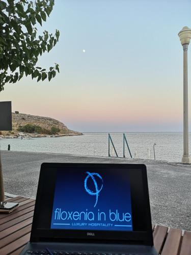 a laptop computer sitting on a bench next to the beach at Relax Seaside House by living in blue in Haraki