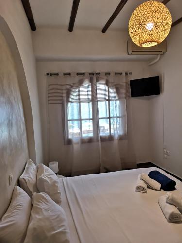 a bedroom with a large white bed with a window at Relax Seaside House by living in blue in Haraki