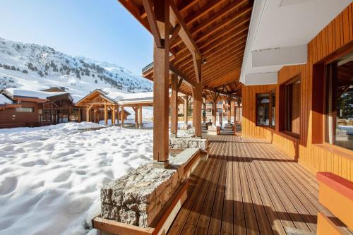 a wooden porch of a ski lodge with snow on the ground at Résidence Pierre & Vacances Premium les Crets in Les Allues