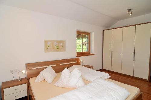 una camera da letto con letto, lenzuola e cuscini bianchi di Weinhof Mumelter ad Appiano sulla Strada del Vino